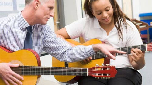 A guitar tutor teaches a young student